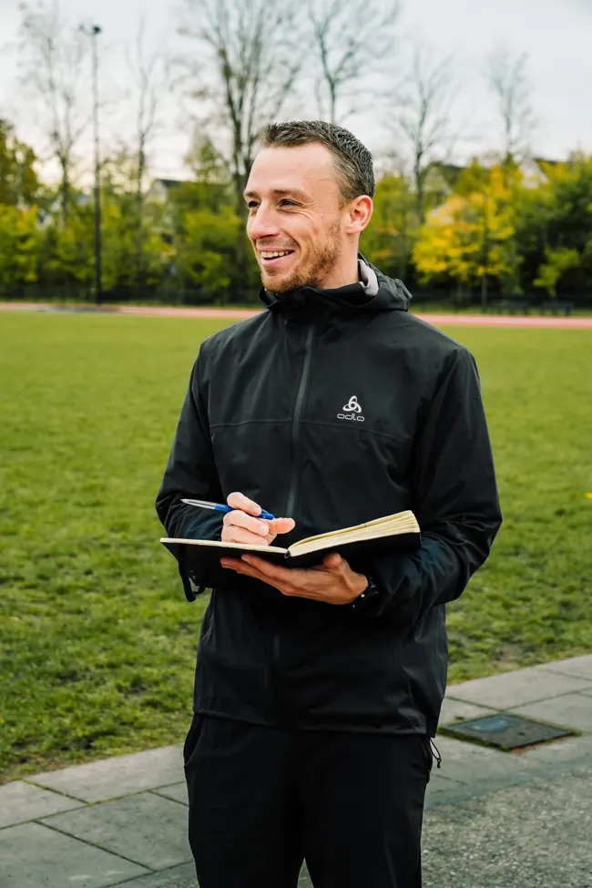 Thijs met zijn notitieboek tijdens een gesprek op de atletiekbaan